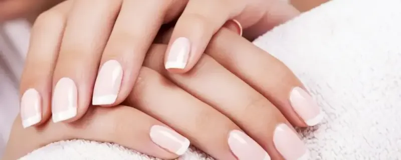 Jasny manicure na dłoniach opartych na ręczniku